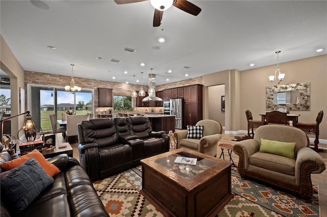 living area with plenty of natural light, recessed lighting, ceiling fan with notable chandelier, and visible vents