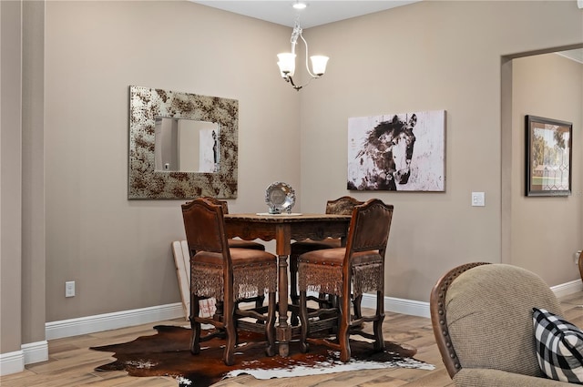 dining space featuring baseboards, an inviting chandelier, and wood finished floors