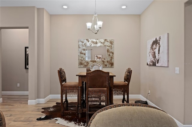 dining room with light wood-type flooring, recessed lighting, baseboards, and a notable chandelier