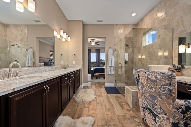 bathroom with connected bathroom, a sink, a ceiling fan, wood finished floors, and tiled shower