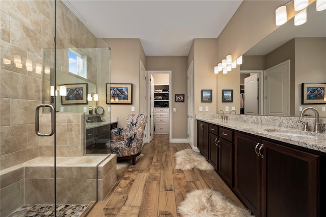 full bathroom featuring a sink, wood-type flooring, a stall shower, and double vanity