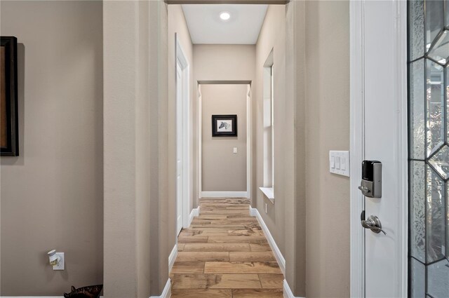 corridor with light wood-style floors and baseboards
