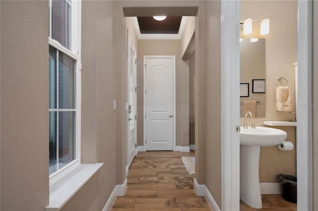 hallway with baseboards, ornamental molding, and wood finished floors