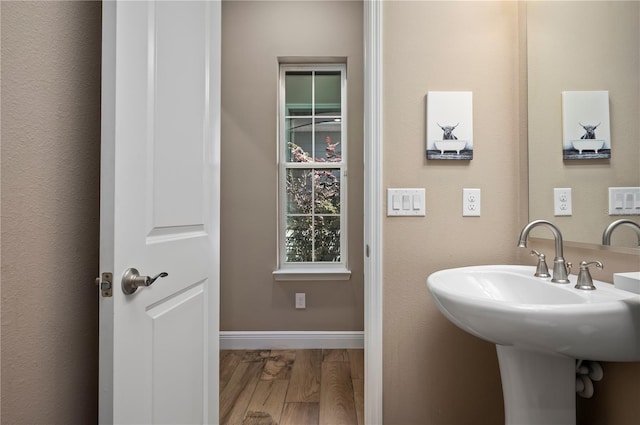 bathroom featuring baseboards, a sink, and wood finished floors