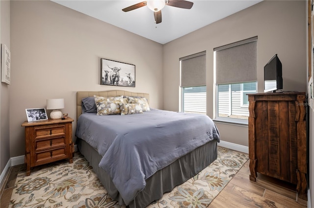 bedroom featuring a ceiling fan, baseboards, and light wood-style floors