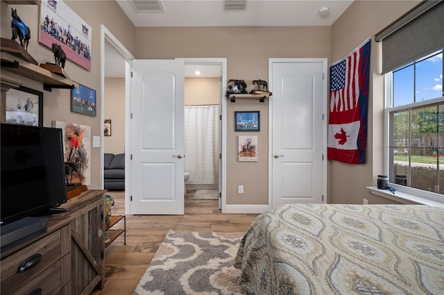 bedroom featuring baseboards, visible vents, and wood finished floors