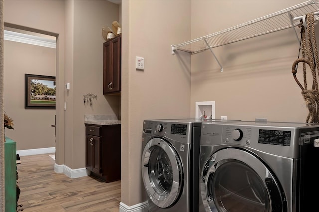 washroom with baseboards, cabinet space, light wood-style flooring, and washer and clothes dryer