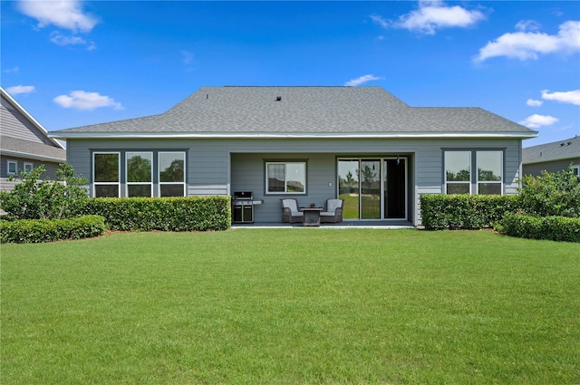 rear view of property with a shingled roof, a patio area, and a yard