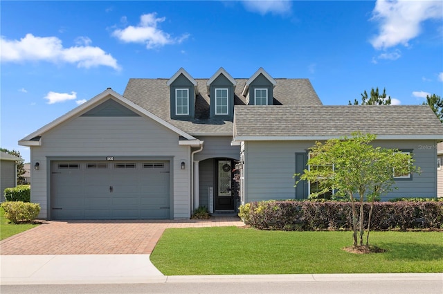 view of front of property featuring decorative driveway, a garage, a front yard, and a shingled roof
