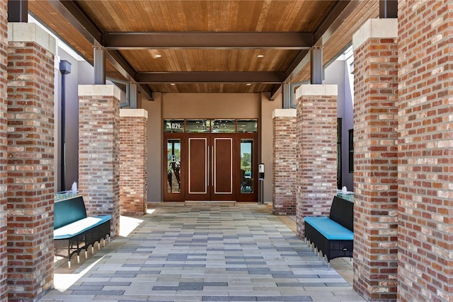 view of exterior entry featuring french doors, stucco siding, and brick siding