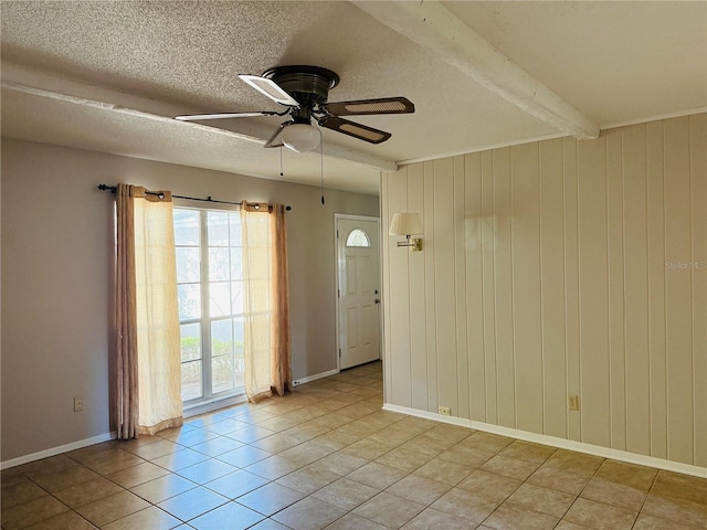unfurnished room featuring a textured ceiling, beamed ceiling, a ceiling fan, light tile patterned floors, and baseboards