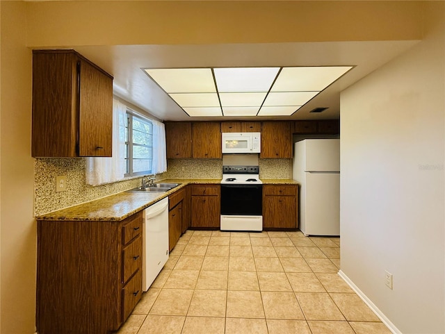 kitchen featuring light tile patterned floors, white appliances, visible vents, a sink, and tasteful backsplash