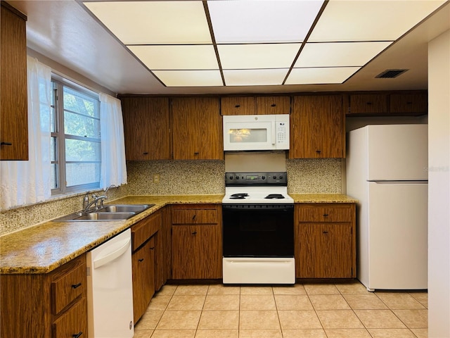 kitchen with white appliances, a sink, light countertops, and light tile patterned floors