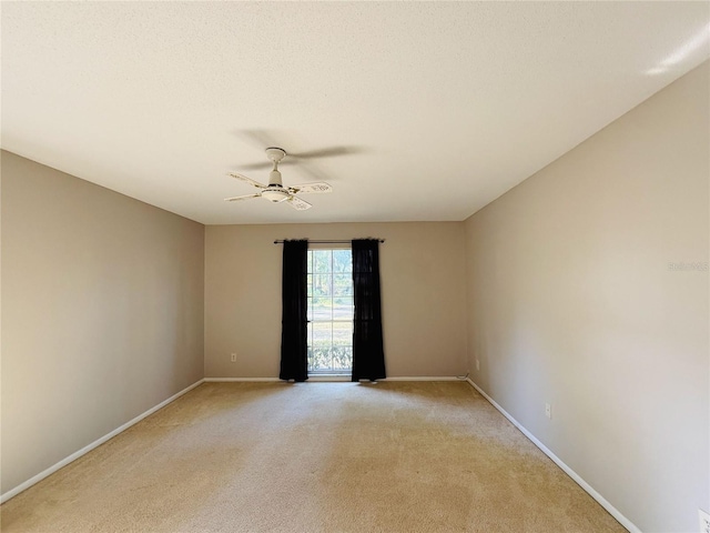 empty room featuring light carpet, baseboards, and a ceiling fan
