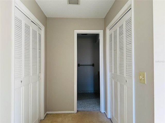 corridor featuring light colored carpet and baseboards