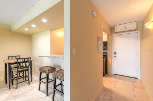 hall featuring light tile patterned floors, baseboards, and recessed lighting
