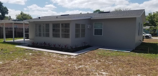 rear view of property featuring stucco siding, roof with shingles, fence, and a lawn