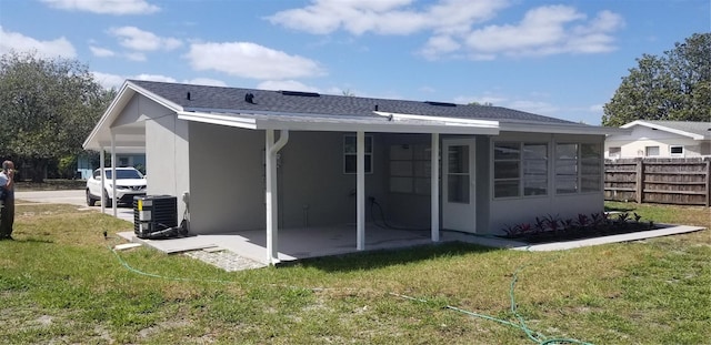 rear view of property featuring a yard, central AC unit, fence, and a patio area