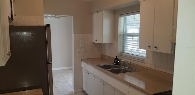 kitchen featuring freestanding refrigerator, white cabinets, a ceiling fan, and a sink
