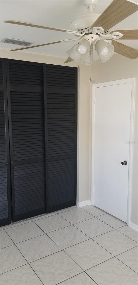 empty room featuring light tile patterned floors, baseboards, and ceiling fan