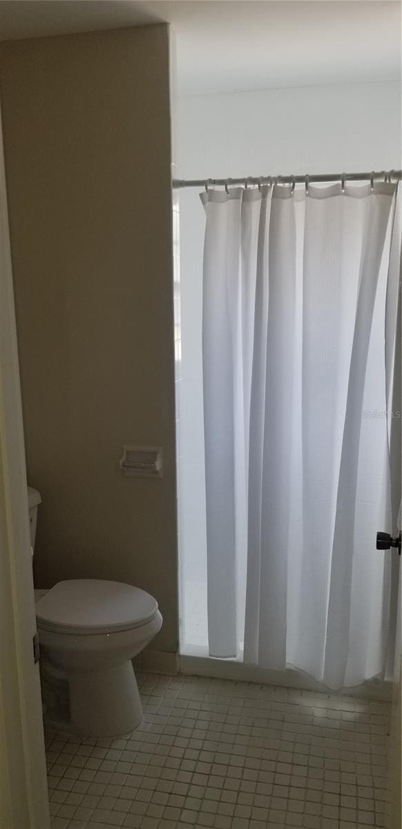 full bath with toilet, tile patterned flooring, and a shower with shower curtain