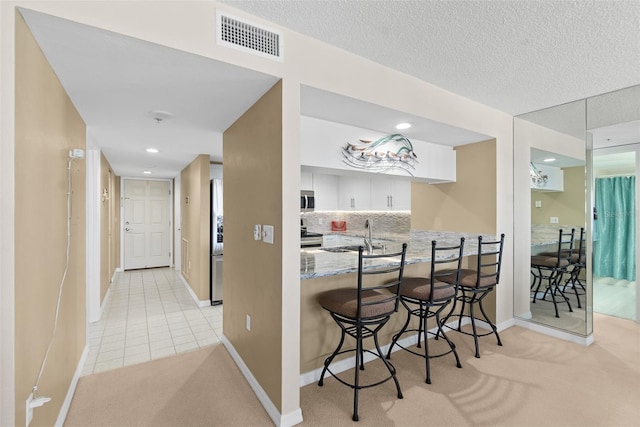 2967 S Atlantic Ave Unit 1601, Daytona Beach Shores, FL 32118 - kitchen featuring a sink, a kitchen breakfast bar, visible vents, light colored carpet, and appliances with stainless steel finishes