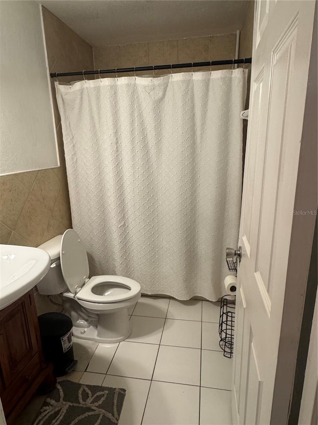 full bathroom with tile walls, toilet, tile patterned flooring, and vanity
