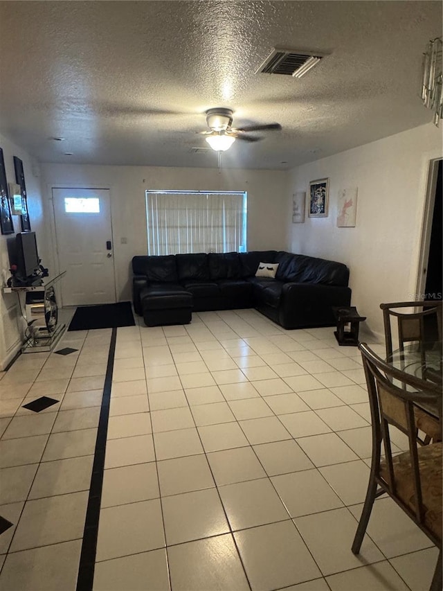 living area with a textured ceiling, a ceiling fan, and light tile patterned floors