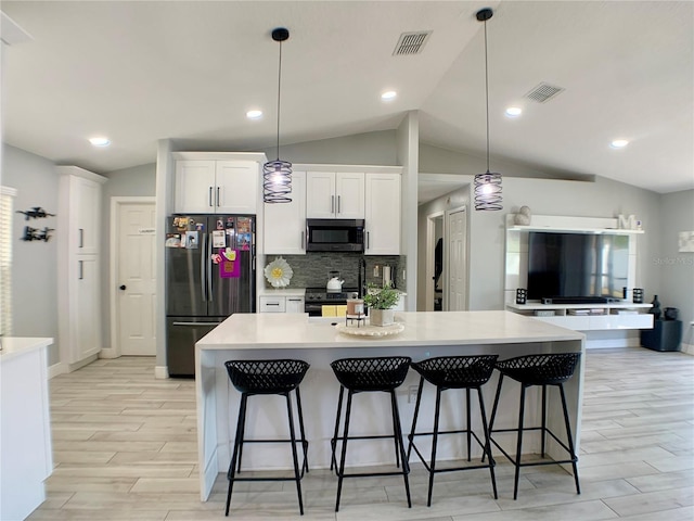 kitchen with vaulted ceiling, appliances with stainless steel finishes, visible vents, and light wood-style flooring