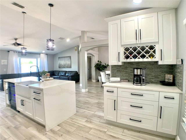 kitchen featuring tasteful backsplash, visible vents, ceiling fan, open floor plan, and arched walkways