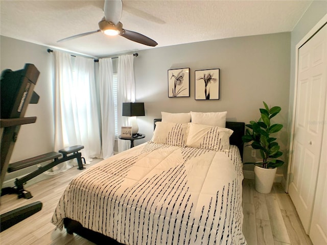 bedroom with ceiling fan, a textured ceiling, baseboards, and light wood-type flooring