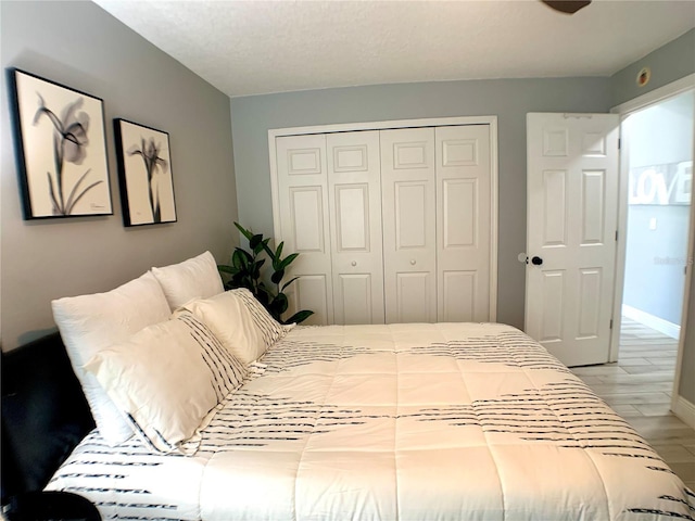 bedroom with light wood finished floors, a closet, and baseboards