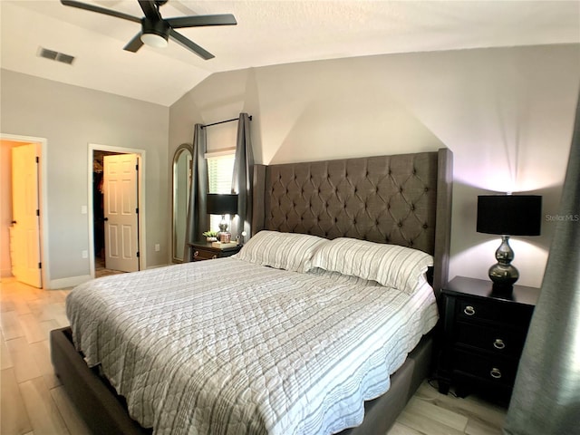 bedroom with light wood-style flooring, a walk in closet, visible vents, baseboards, and lofted ceiling