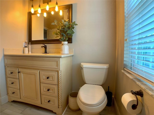 half bathroom featuring vanity, toilet, and baseboards