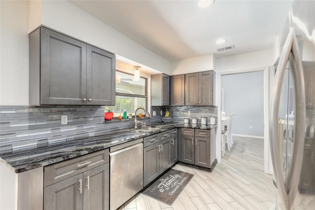 85 Pheasant Dr, Palm Coast, FL 32164 - kitchen featuring appliances with stainless steel finishes, dark stone countertops, a sink, decorative backsplash, and baseboards