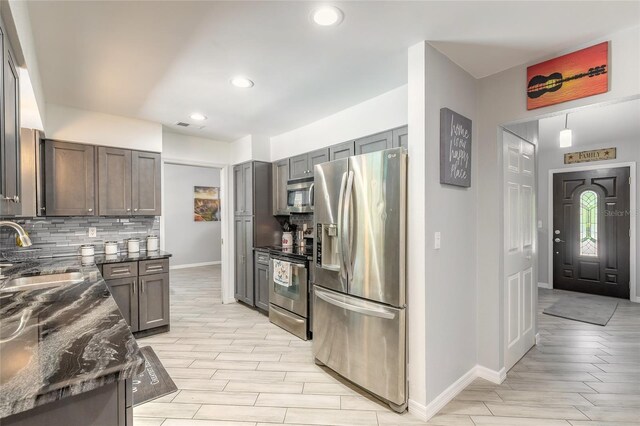 85 Pheasant Dr, Palm Coast, FL 32164 - kitchen featuring appliances with stainless steel finishes, a sink, baseboards, backsplash, and dark stone countertops