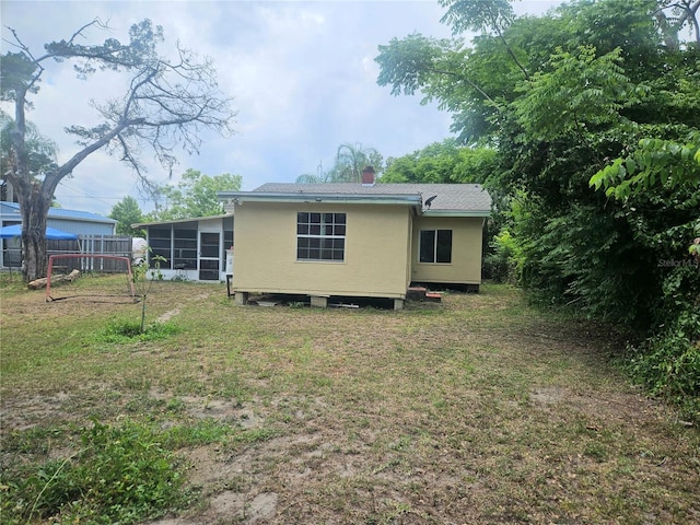 317 Inwood Ave, New Smyrna Beach, FL 32168 - back of house featuring a sunroom, a lawn, and a chimney