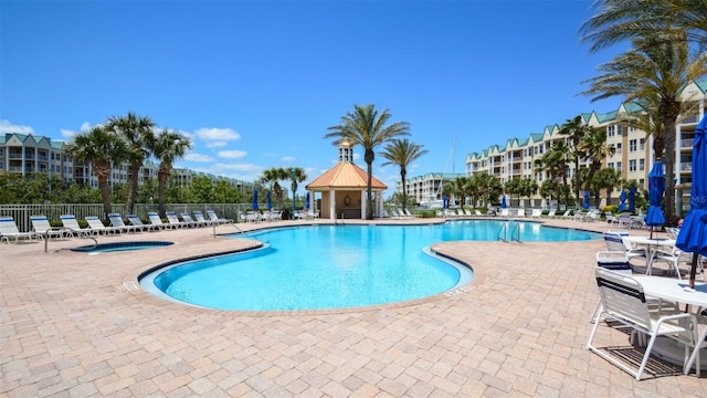 community pool featuring a hot tub, fence, and a patio