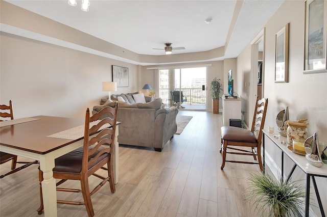 interior space with light wood-style flooring, a raised ceiling, and ceiling fan