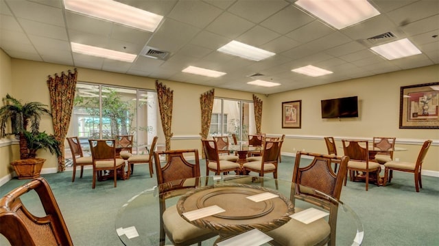 carpeted dining space with baseboards, a paneled ceiling, and visible vents