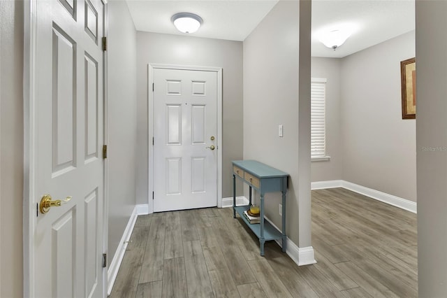 doorway to outside featuring baseboards and wood finished floors