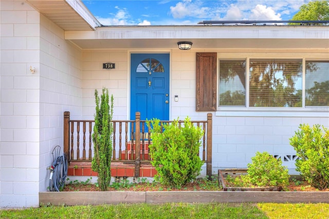 doorway to property with concrete block siding and covered porch