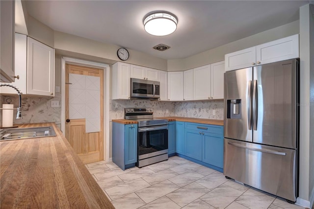 kitchen with appliances with stainless steel finishes, wood counters, blue cabinetry, a sink, and white cabinets