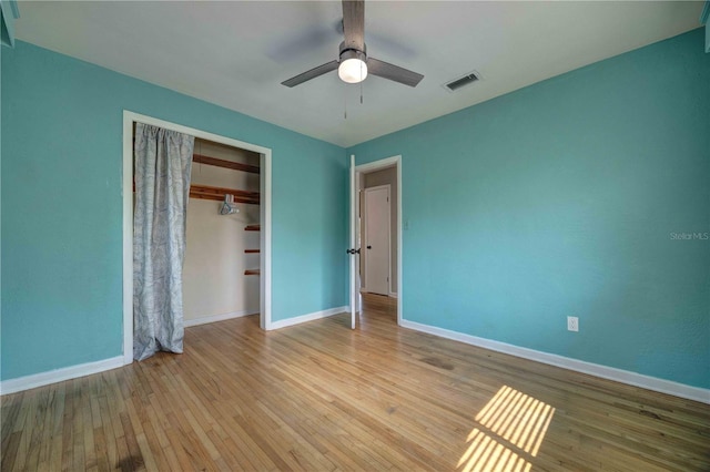 unfurnished bedroom featuring wood finished floors, baseboards, a closet, and a ceiling fan