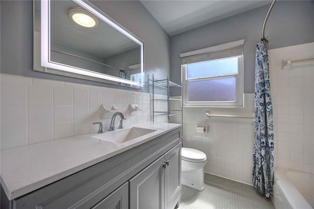 bathroom featuring toilet, tile patterned flooring, tile walls, vanity, and wainscoting