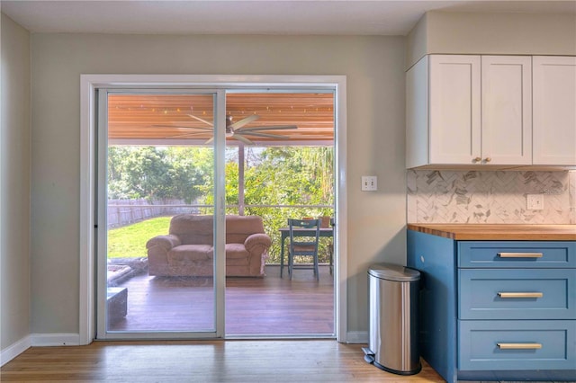 doorway to outside with light wood-style flooring, ceiling fan, and baseboards
