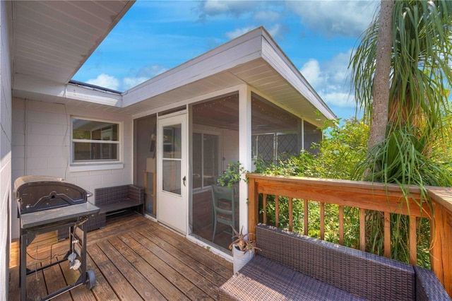 wooden terrace with a sunroom and a grill