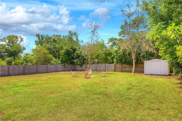 view of yard featuring a storage shed, an outbuilding, and view of wooded area