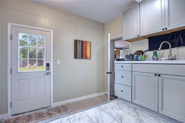 kitchen featuring baseboards, light countertops, and a sink