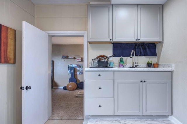 kitchen with light countertops, baseboards, a sink, and gray cabinets